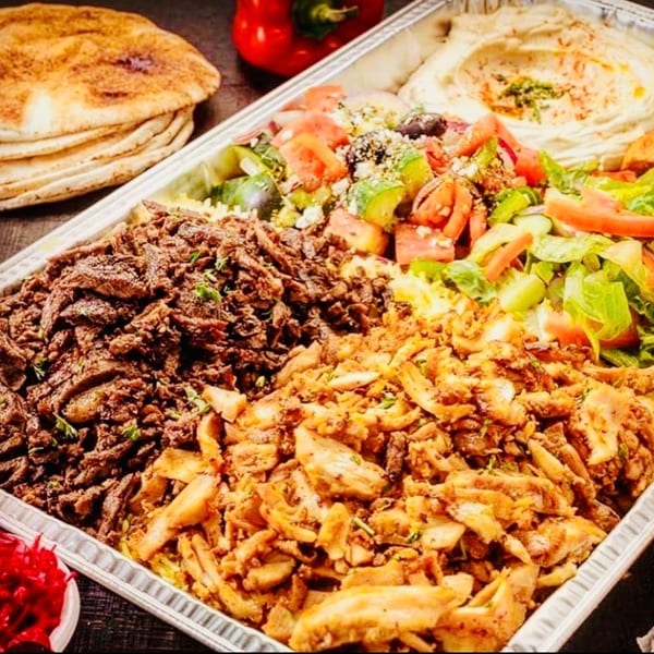 Large platter with beef and chicken shawarma, hummus, salads, and pita bread.